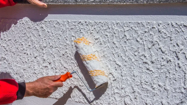 Application de peinture au rouleau sur une façade en crépi